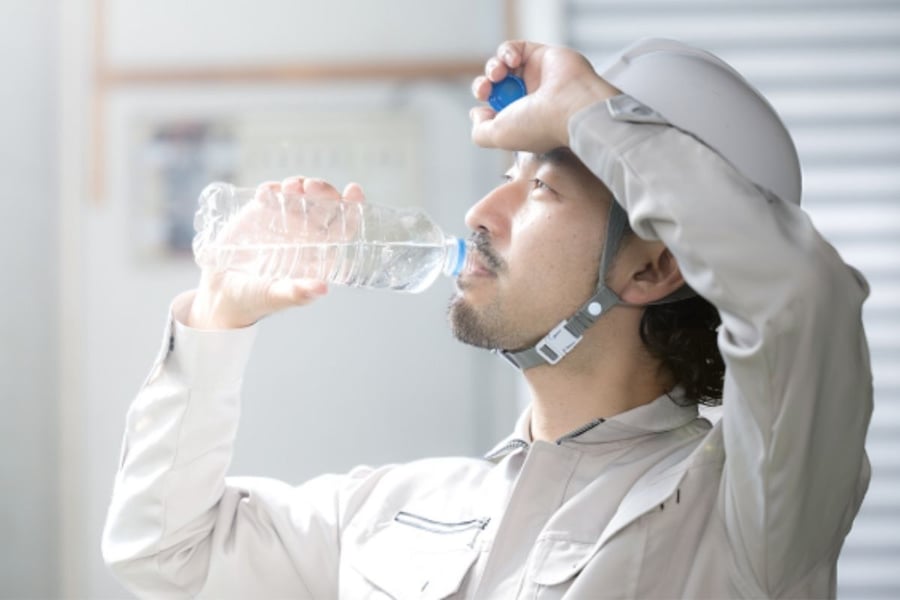 水のペットボトルを飲んでいるヘルメットをかぶった男性