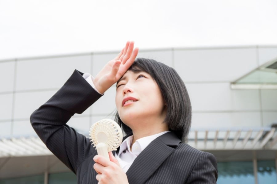 ハンディ扇風機をもつスーツの女性